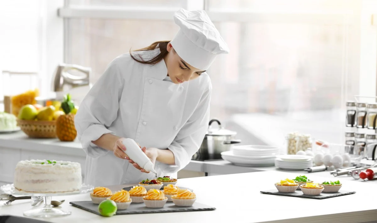 chef pasticceria che rifinisce piccole monoporzioni con cioccolato fuso