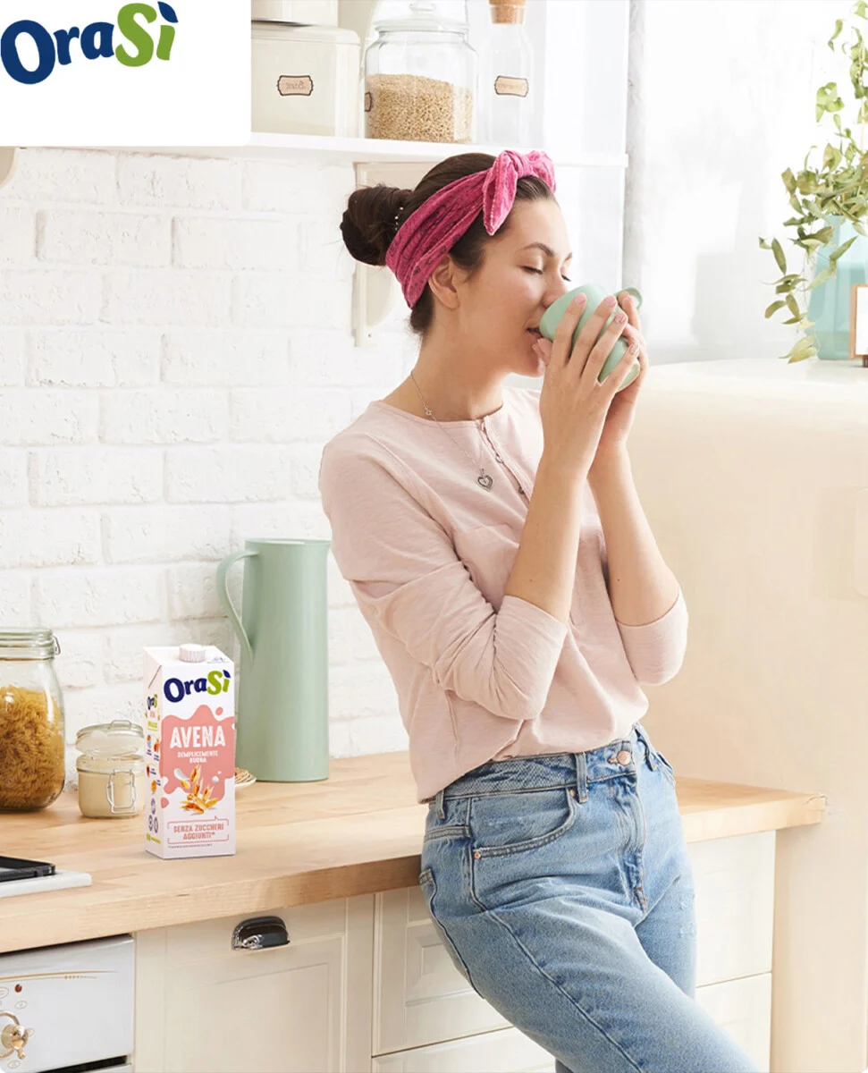 banner oraSì donna che beve una tazza di bevanda vegetale in cucina chiara