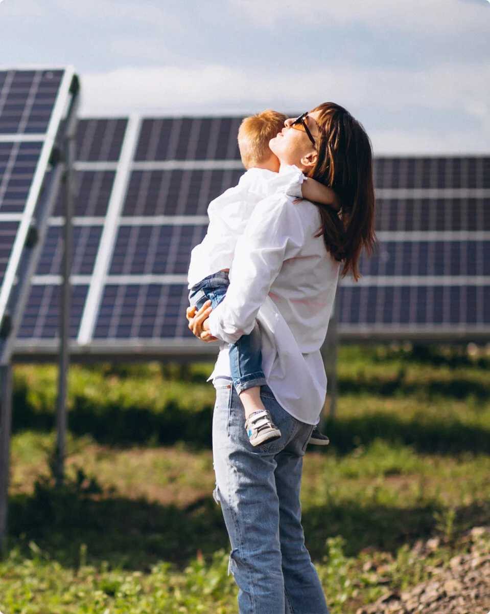 donna con in braccio un bambino e pannelli fotovoltaici di sfondo